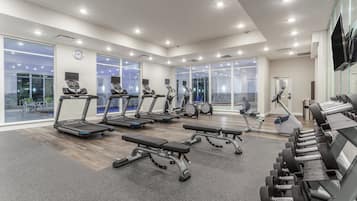 A modern gym with treadmills, benches, and dumbbells.