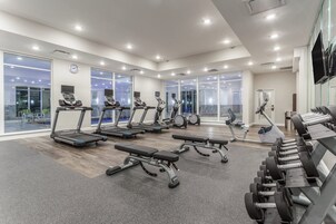 Un gimnasio moderno con cintas de correr, bancos y mancuernas.