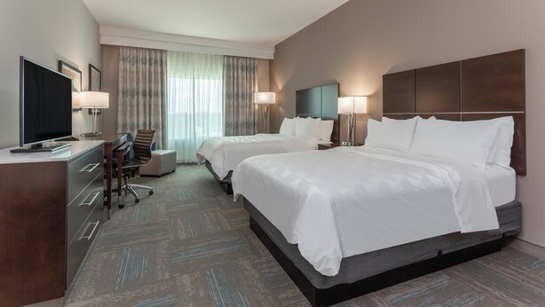 Een hotelkamer met twee bedden, een bureau, een televisie en een stoel.
