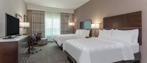Une chambre d’hôtel avec deux lits, un bureau, une télévision et une chaise.