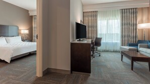 Een hotelkamer met een bed, bureau, televisie en zithoek.