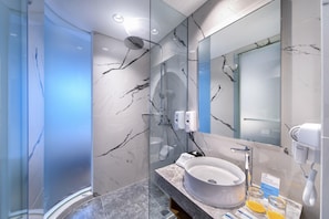 A modern bathroom with a glass-enclosed shower, a marble-tiled wall, a large sink, and a hairdryer on the counter. - Holiday Inn Express Jakarta Menteng by IHG (Jakarta)