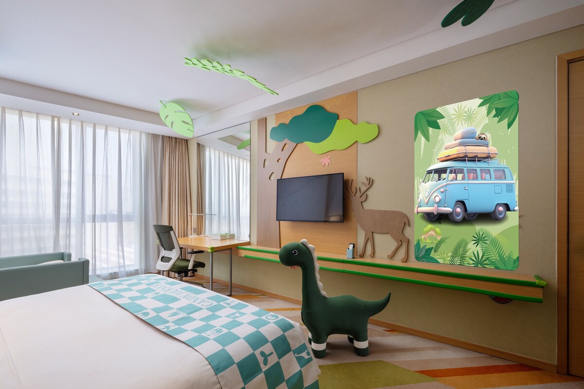A hotel room with a bed, a desk with a chair, a television, and a wall mural.