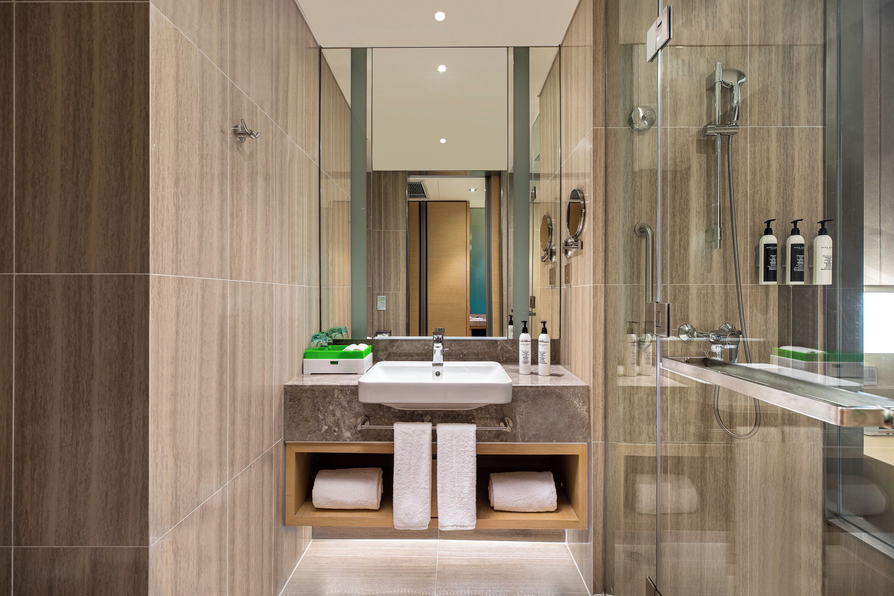 A modern bathroom with a large mirror, a sink, and a shower area.