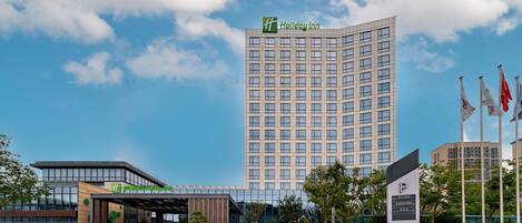 A modern Holiday Inn hotel with a prominent 'P' sign for parking, a clear sky, and a well-maintained entrance area.