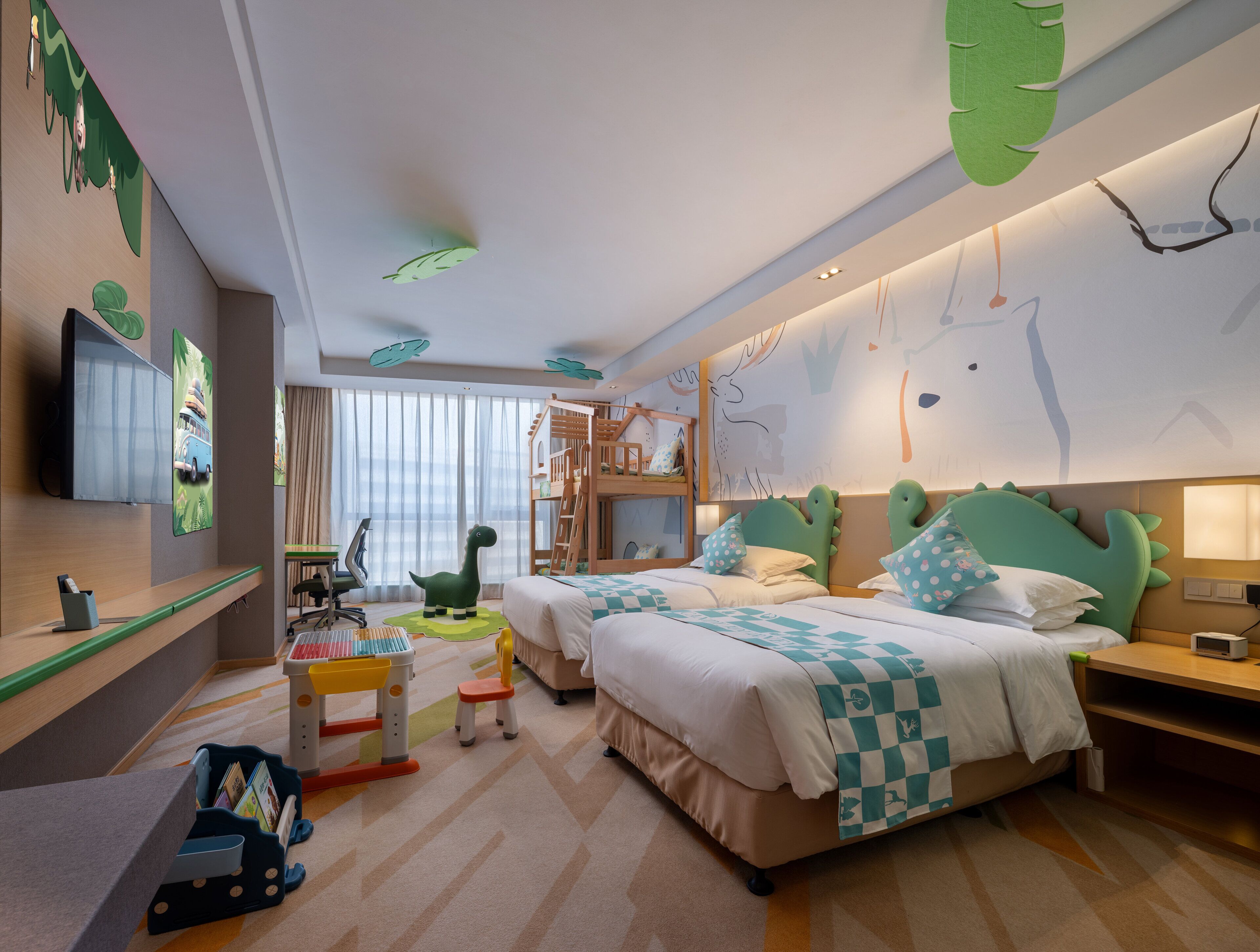 Habitación de hotel ideal para niños, con literas, escritorio, televisión y zona de juegos.