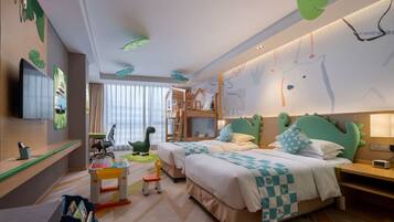 Habitación de hotel ideal para niños, con literas, escritorio, televisión y zona de juegos.