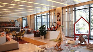 Eine moderne Hotelhalle mit Sitzgelegenheiten, einer Bar und großen Fenstern mit Blick ins Freie.