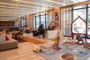 A modern hotel lobby with a seating area, a bar, and large windows offering a view of the outdoors. - Holiday Inn Wuxi Taihu New City by IHG (Wuxi)