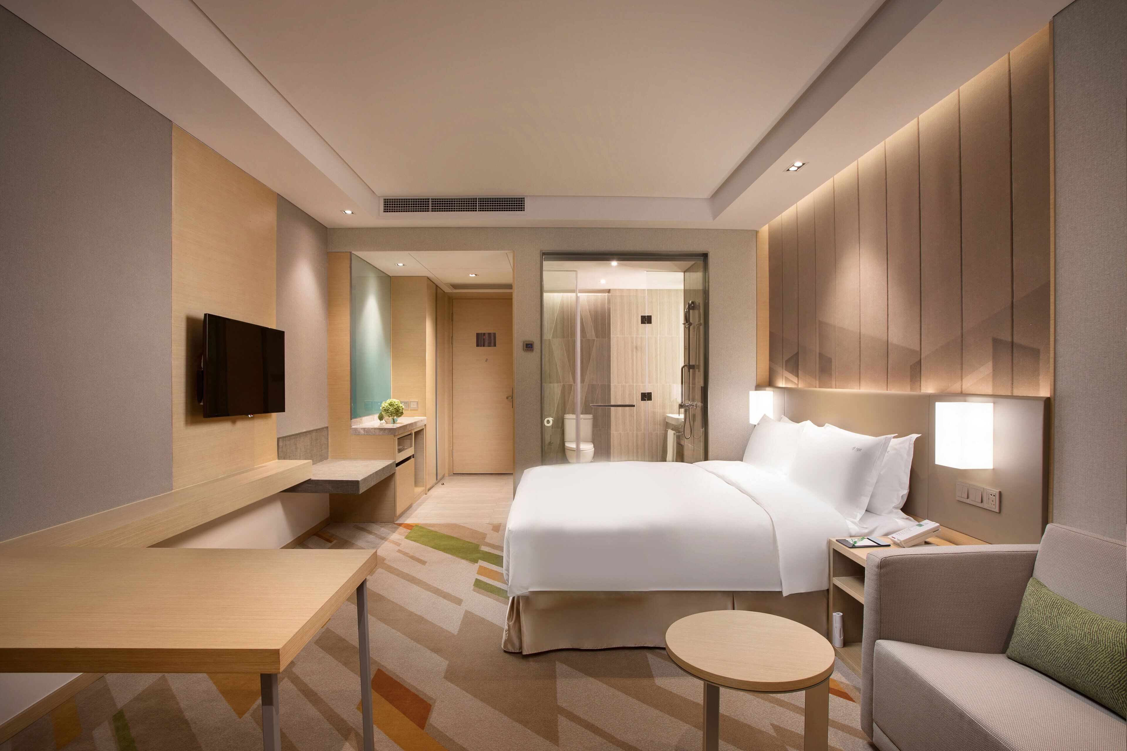 Una habitación de hotel moderna con una cama grande, un escritorio, una silla y una mesita.