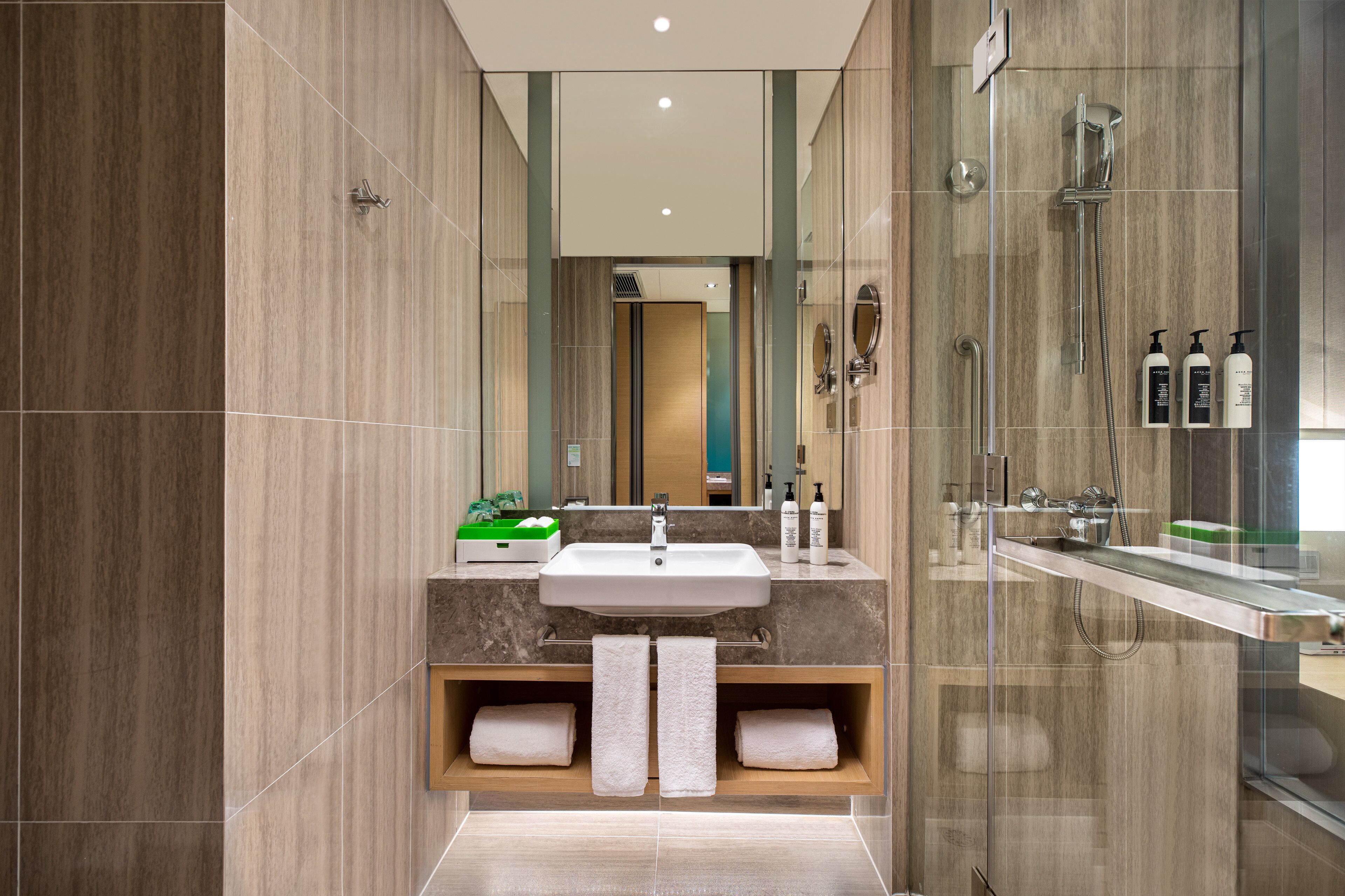 A modern bathroom with a large mirror, a sink, and a glass-enclosed shower area.