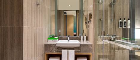 A modern bathroom with a large mirror, a sink, and a glass-enclosed shower area.
