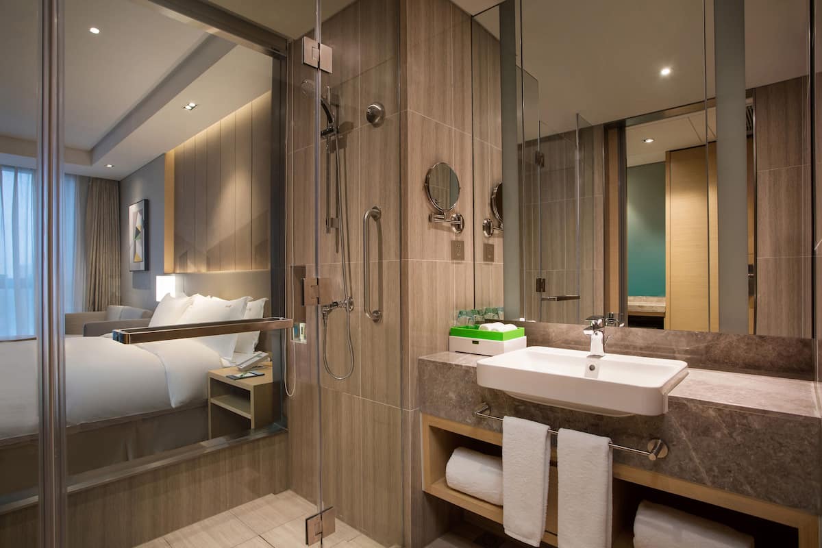 Ein modernes Hotelbad mit Dusche, Waschbecken und großem Spiegel.