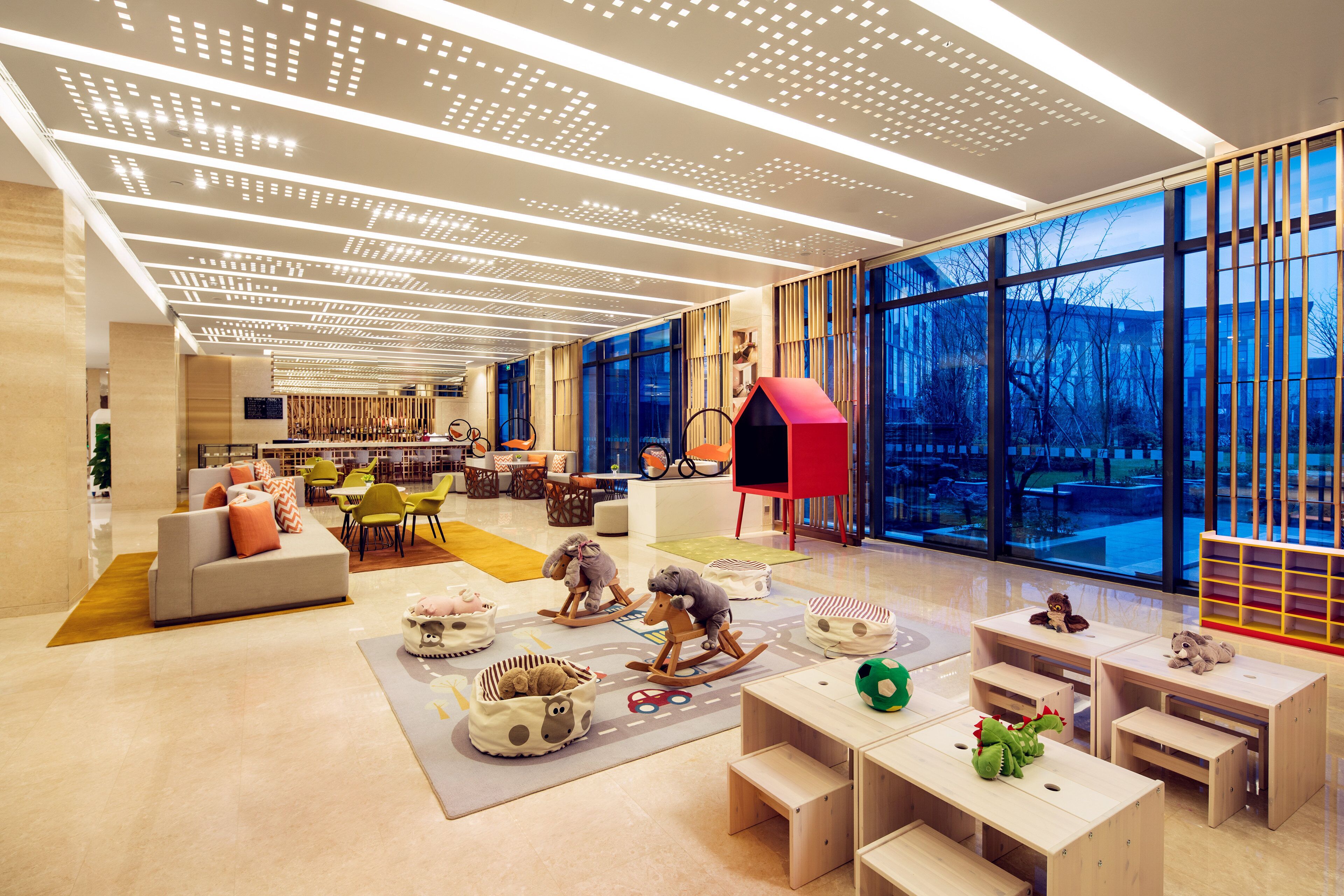A spacious room with a large window, a red playhouse, and a seating area with a sofa and chairs.