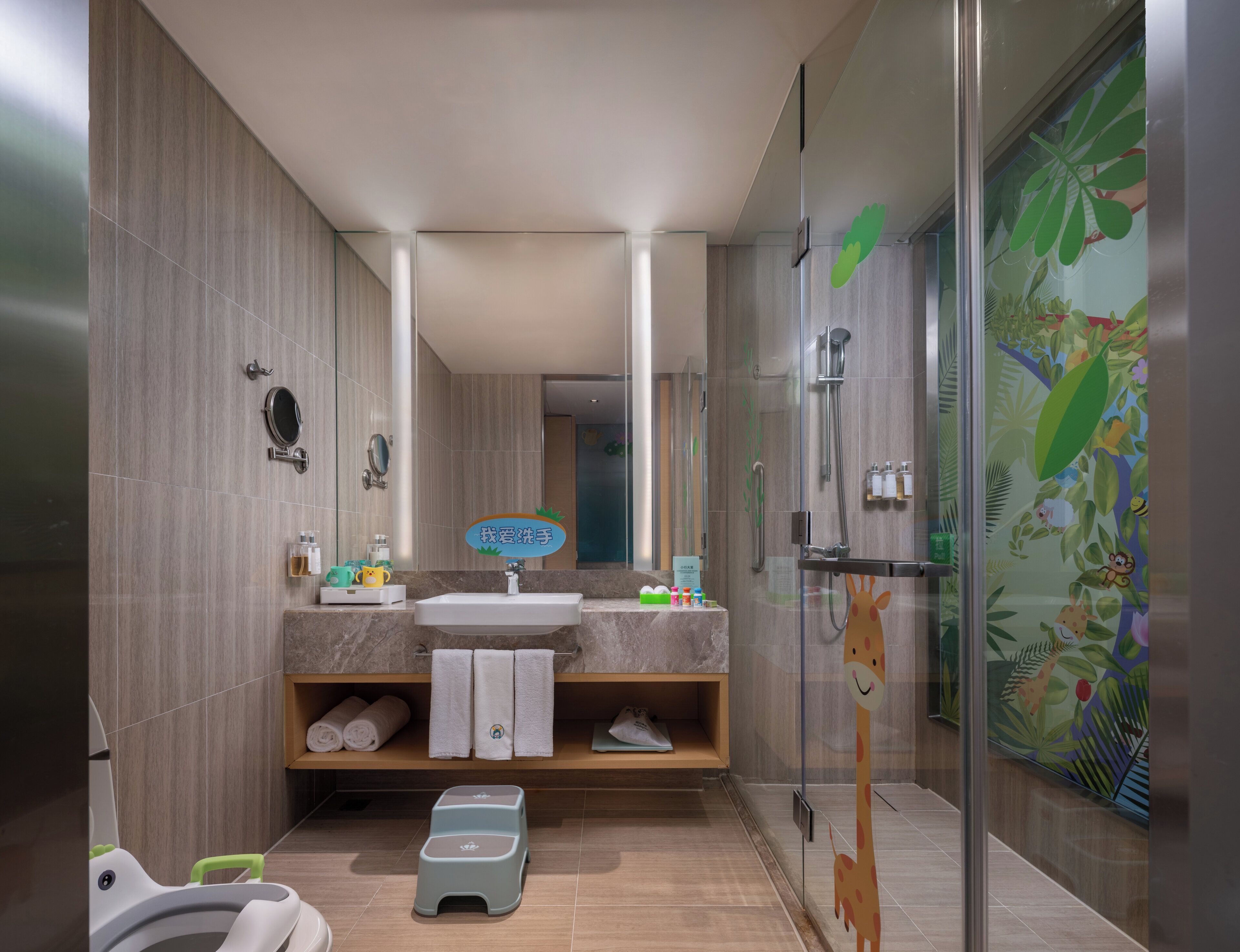 Une salle de bain moderne avec une douche, un lavabo et un miroir. On trouve des serviettes et des articles de toilette sur le comptoir.