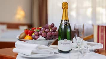 Una mesa servida con una botella de champán, un frutero y una copa.