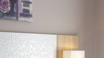 Ein Hotelzimmer mit einem Bett, weißen Kissen, einem Kopfteil mit strukturierter Optik und einer Wandleuchte.