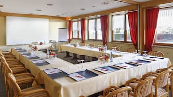 Een vergaderzaal met een lange tafel, stoelen en een projectiescherm.