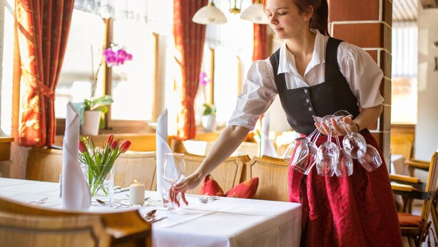 Een restaurantscène waarin een ober een tafel bedient.