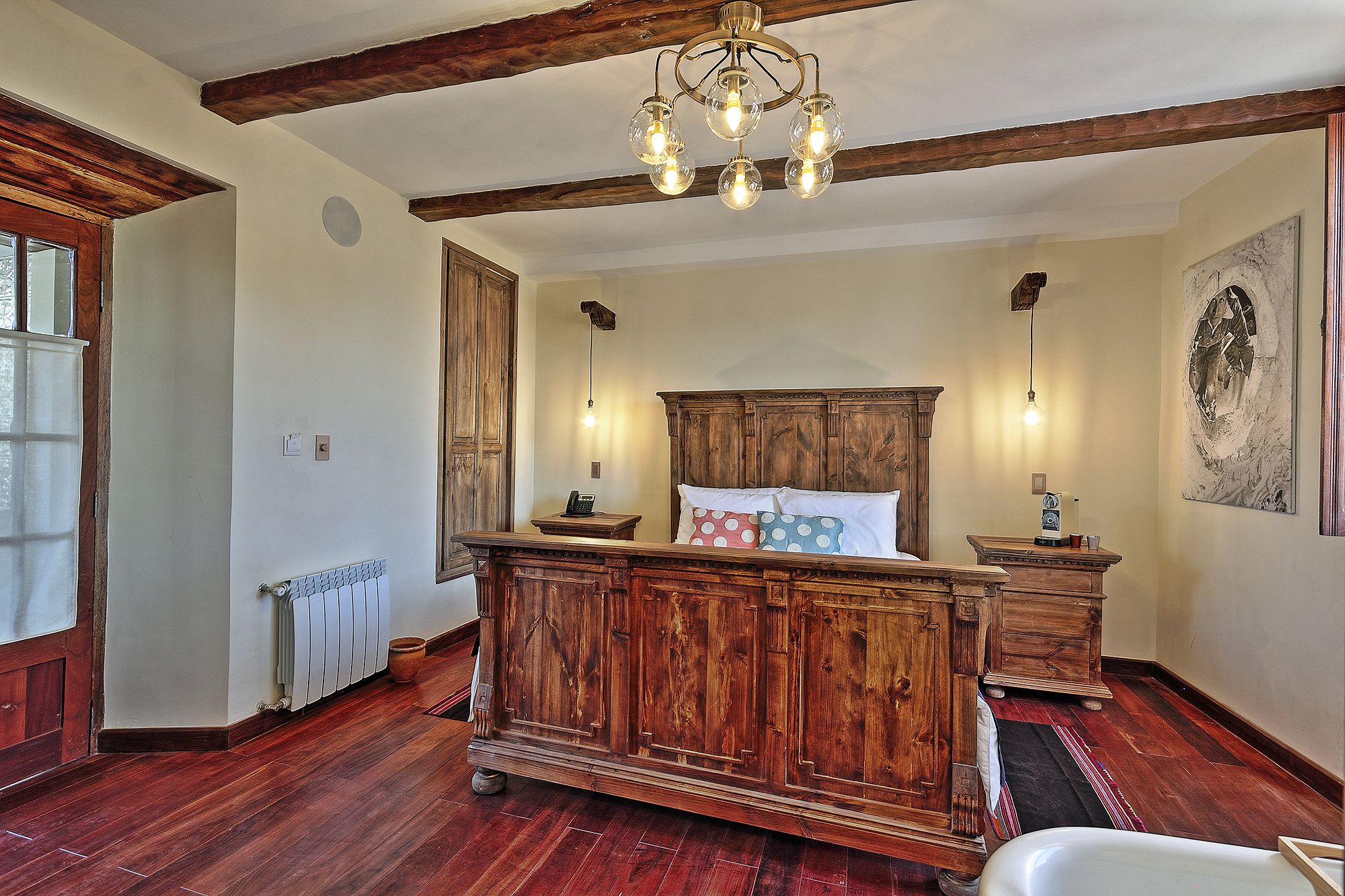 Ein traditionell eingerichtetes Schlafzimmer mit einem hölzernen Himmelbett, einem Heizkörper und einem alten Telefon.