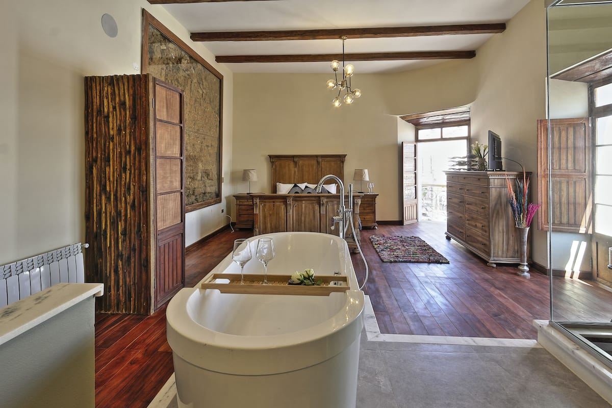 A spacious bathroom with a large bathtub, wooden cabinets, and a chandelier.