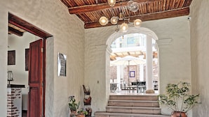 A spacious interior with a wooden ceiling, a staircase leading to an outdoor seating area, and potted plants. - On Hotel Boutique (Sucre)