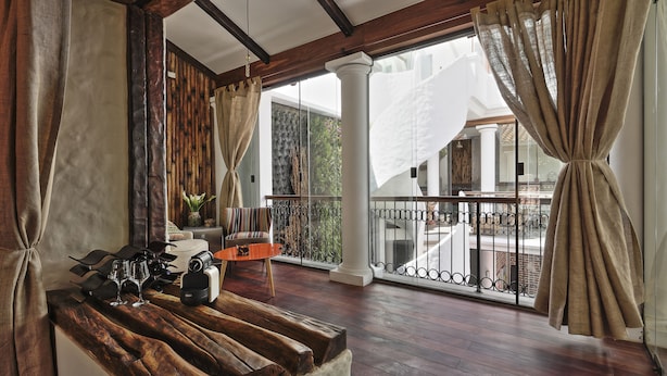 A balcony with a wooden coffee table, a chair, and a potted plant. - On Hotel Boutique (Sucre)