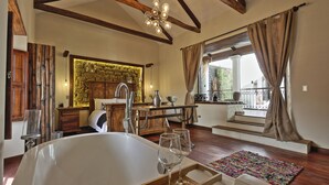 A spacious bathroom with a large bathtub, wooden beams, a stone wall, and a view of the outdoors. - On Hotel Boutique (Sucre)