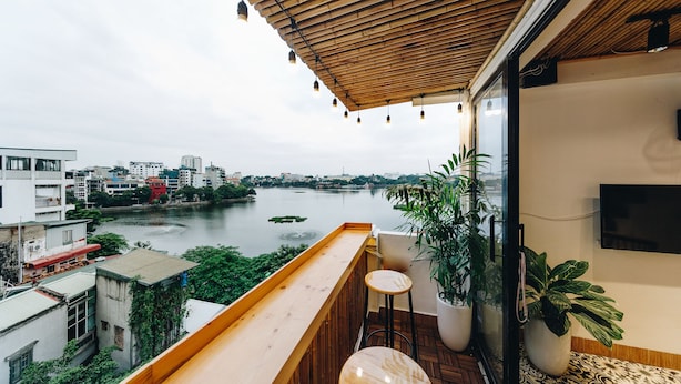 A balcony with a wooden railing, a small stool, and potted plants. - The Autumn Homestay (Hanoi)