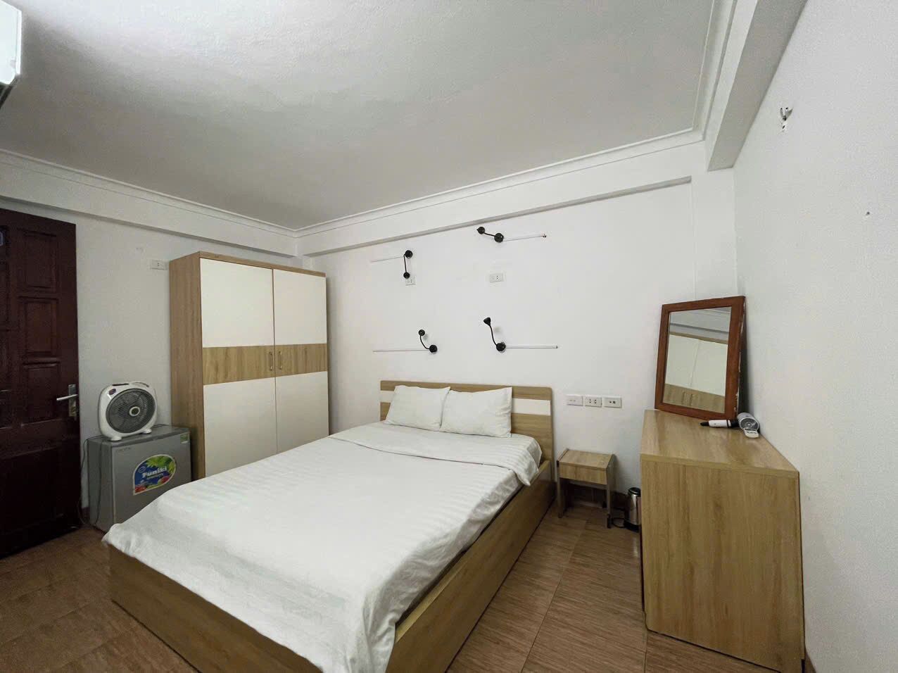 A bedroom with a bed, a wardrobe, a bedside table, a mirror, and a heater.
