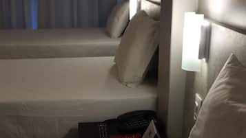 Habitación de hotel con dos camas, cada una con una almohada y una lámpara de noche.