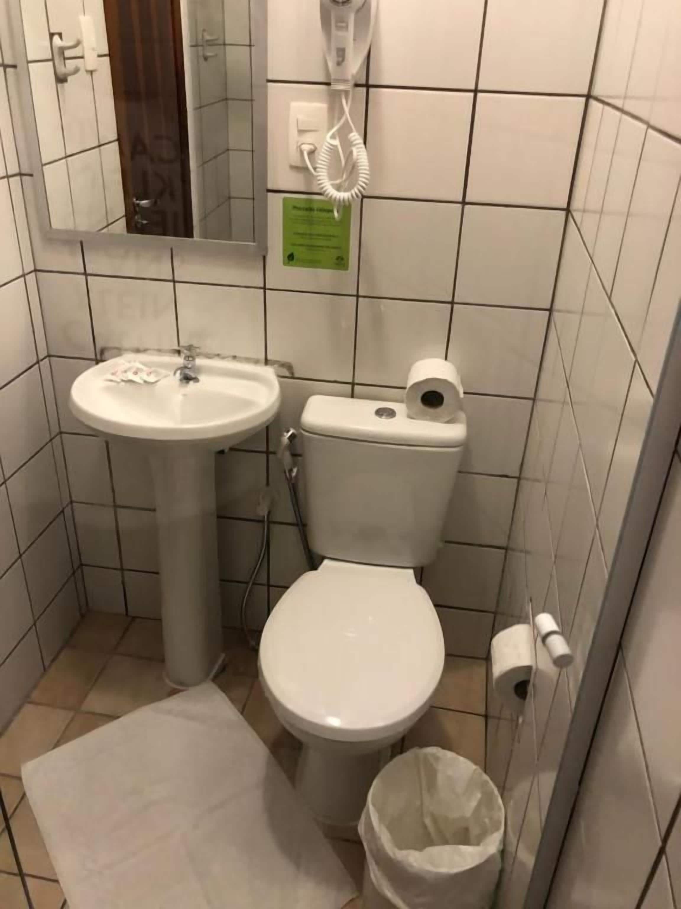 A small bathroom with a sink, toilet, and a hairdryer on the wall.
