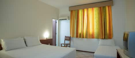Una habitación de hotel con una cama grande, una cama más pequeña, un televisor y un aire acondicionado.