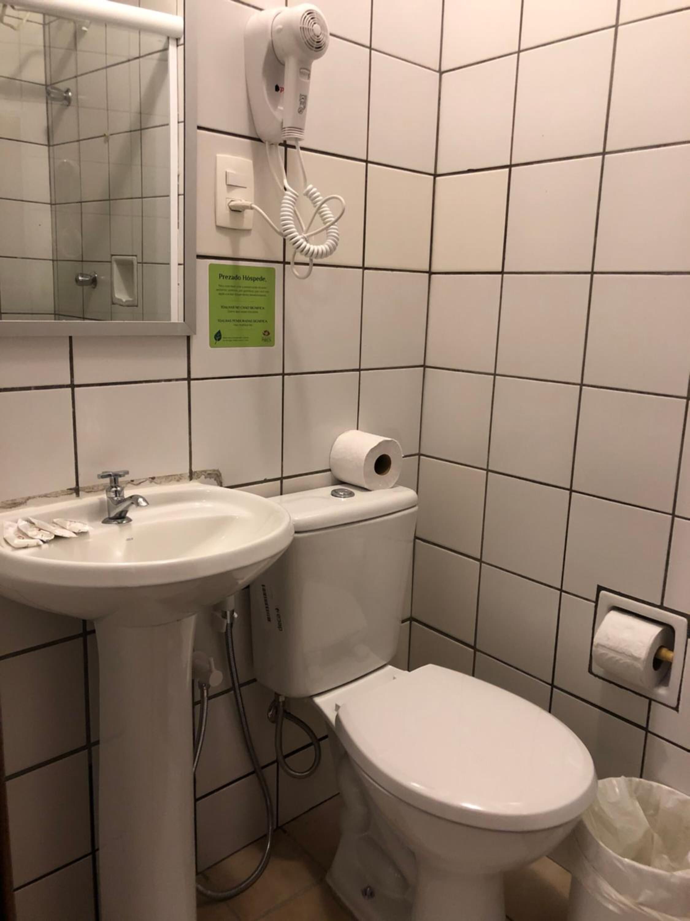 Un baño con lavabo, inodoro y un secador de pelo sujeto a la pared.