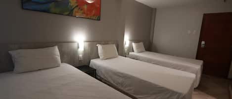 A hotel room with two single beds, a painting on the wall, and a door to the right.