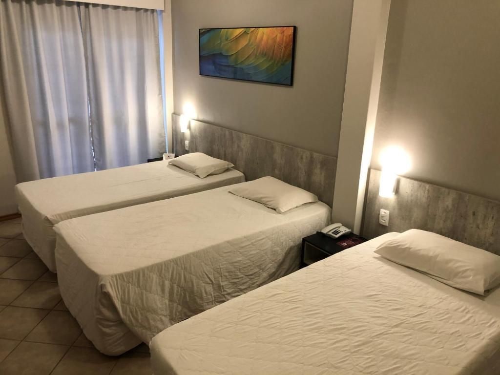 A hotel room with two single beds, a bedside table with a phone, and a painting on the wall.