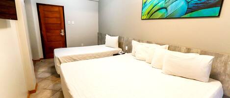 Habitación de hotel con dos camas, una puerta de madera y un cuadro abstracto grande en la pared.
