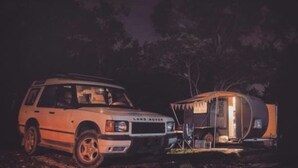 En vit Land Rover stod parkerad bredvid en liten husbil med öppna sidor, och det var natt.