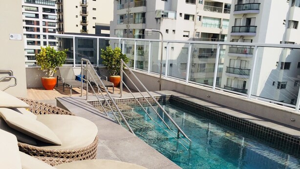 Una piscina en la azotea con sillones de descanso y plantas en macetas.