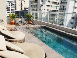 A rooftop pool with lounge chairs and potted plants. - Apartamento Novo Perfeito na Rua Augusta (São Paulo)
