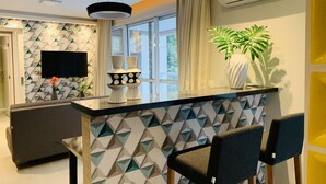 Una cocina moderna con un salpicadero geométrico, una isla central con taburetes de bar, un televisor de pantalla plana y una planta en maceta.