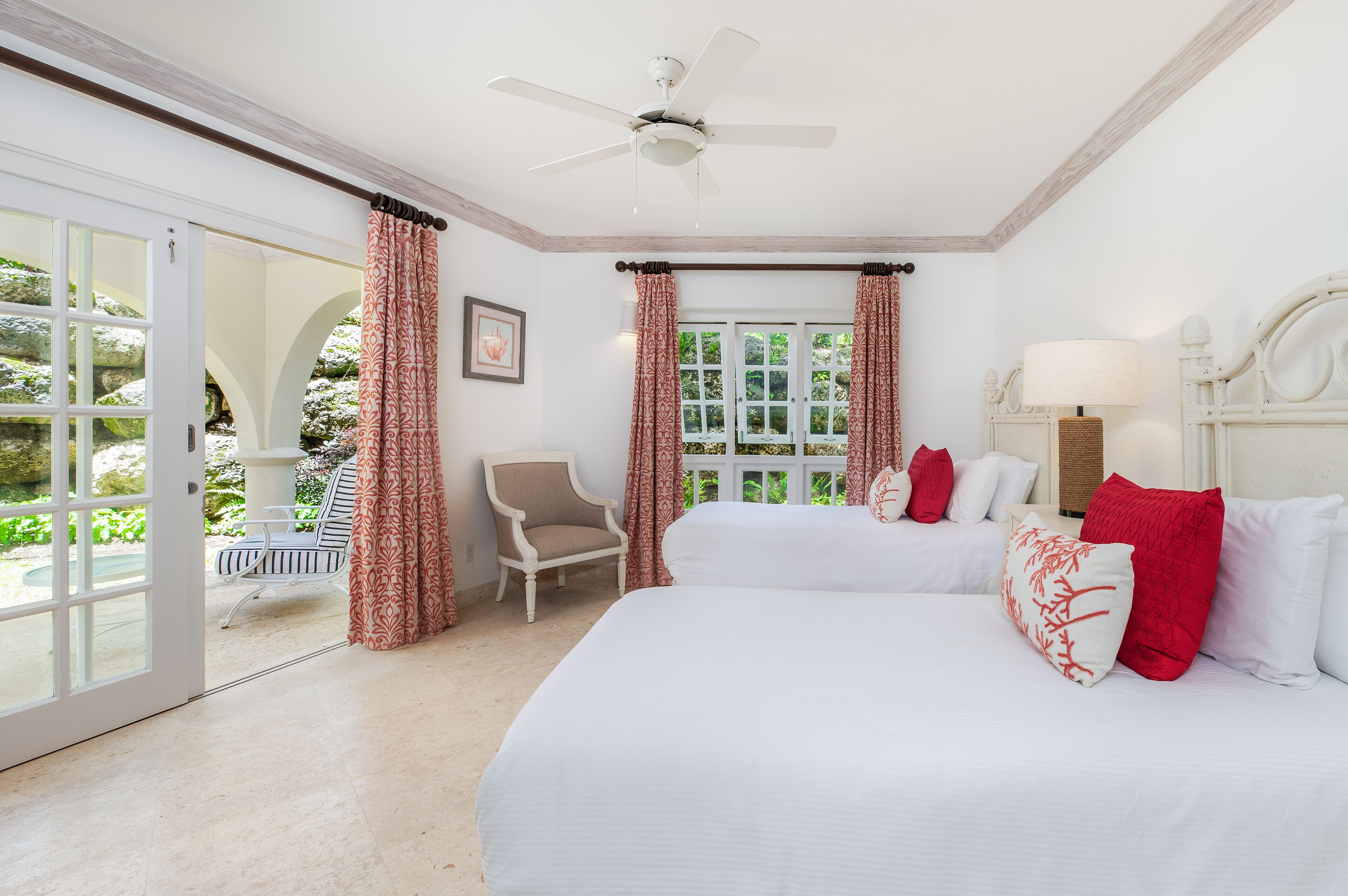 A bedroom with a large bed, a chair, a ceiling fan, and a window with curtains.