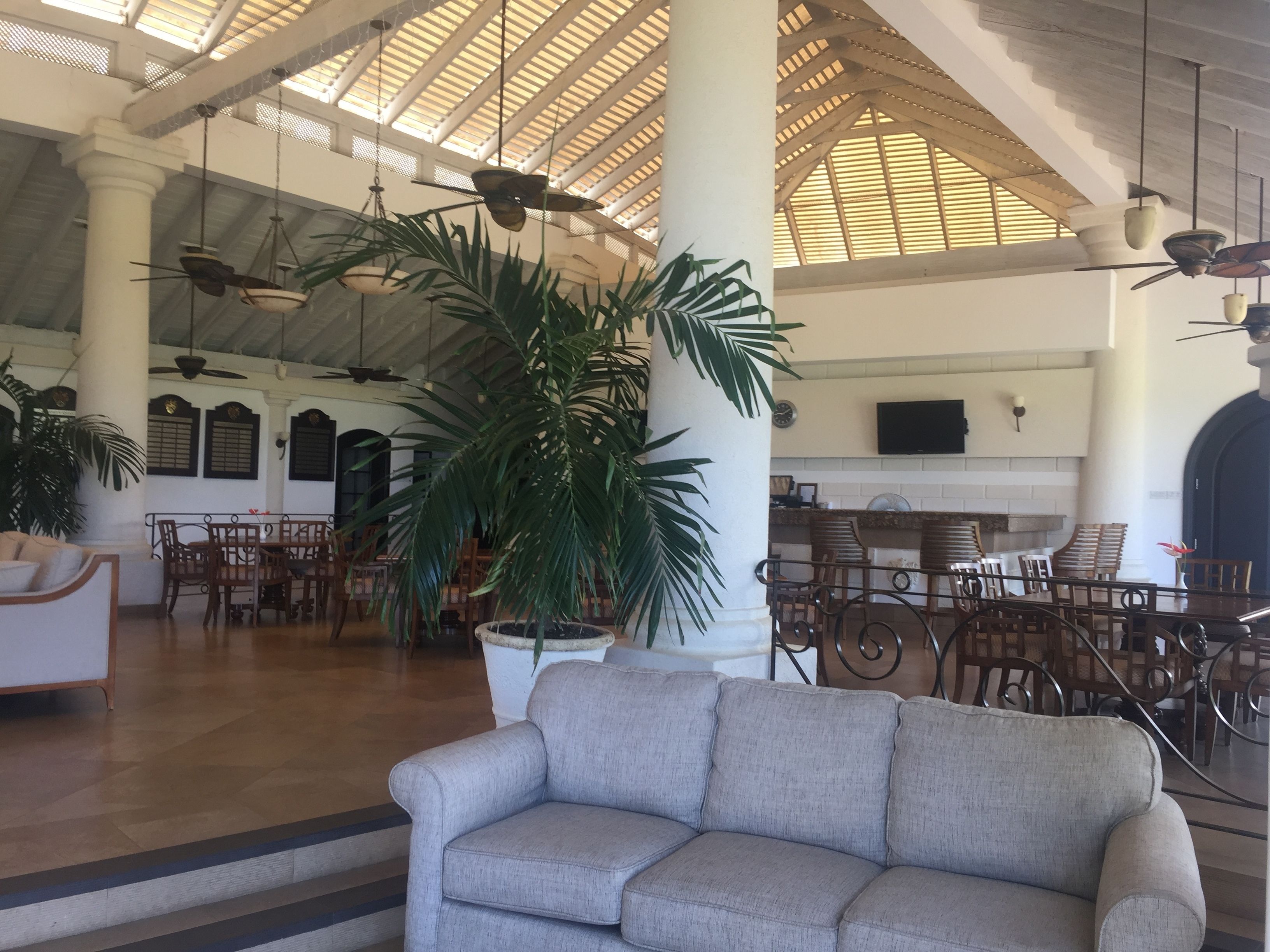 A spacious lobby with high ceilings, large windows, and a central seating area with a sofa and chairs.