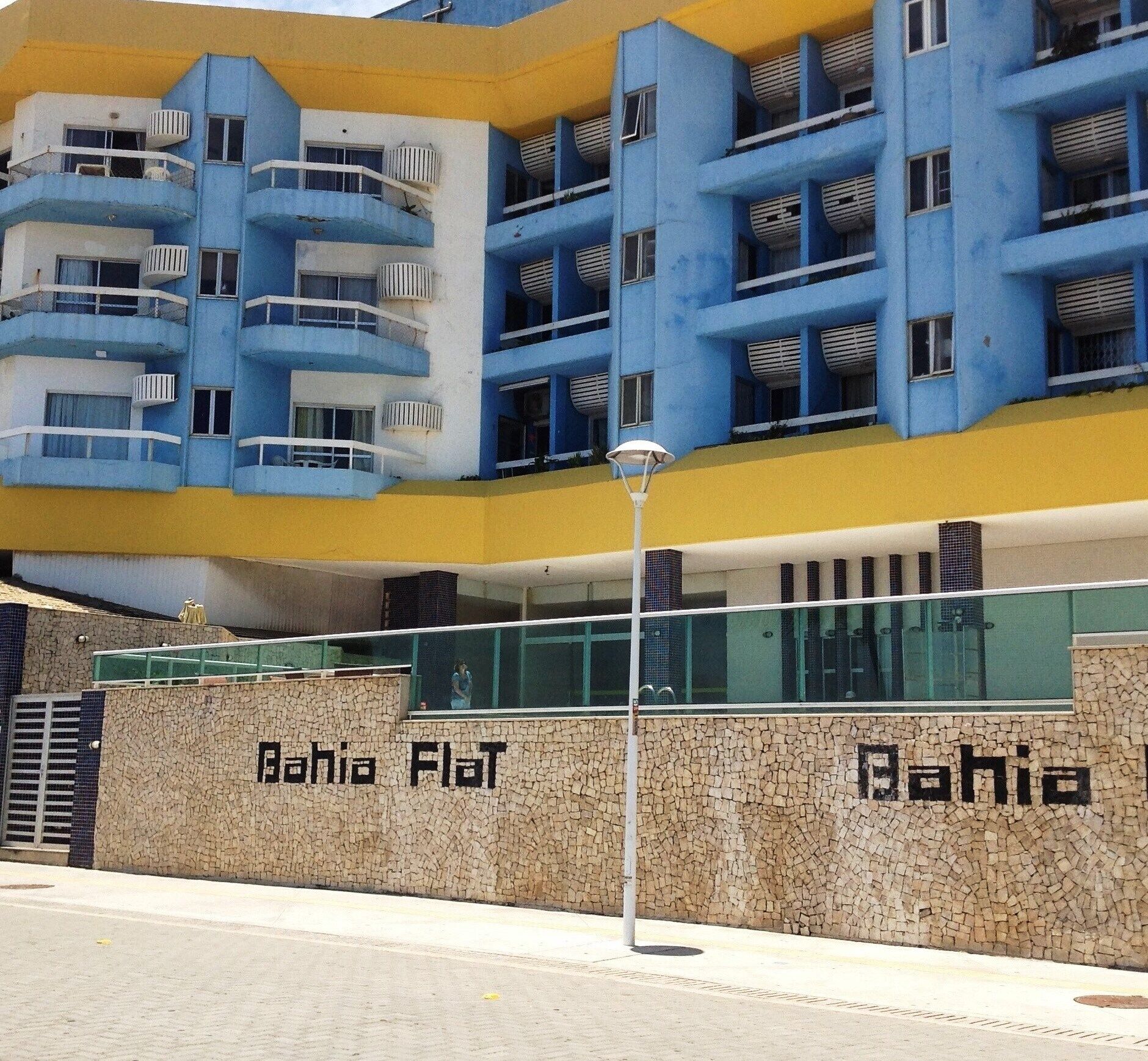 Un edificio moderno con fachada plana, varios balcones y una pared texturizada con el nombre "Bahia Flat".