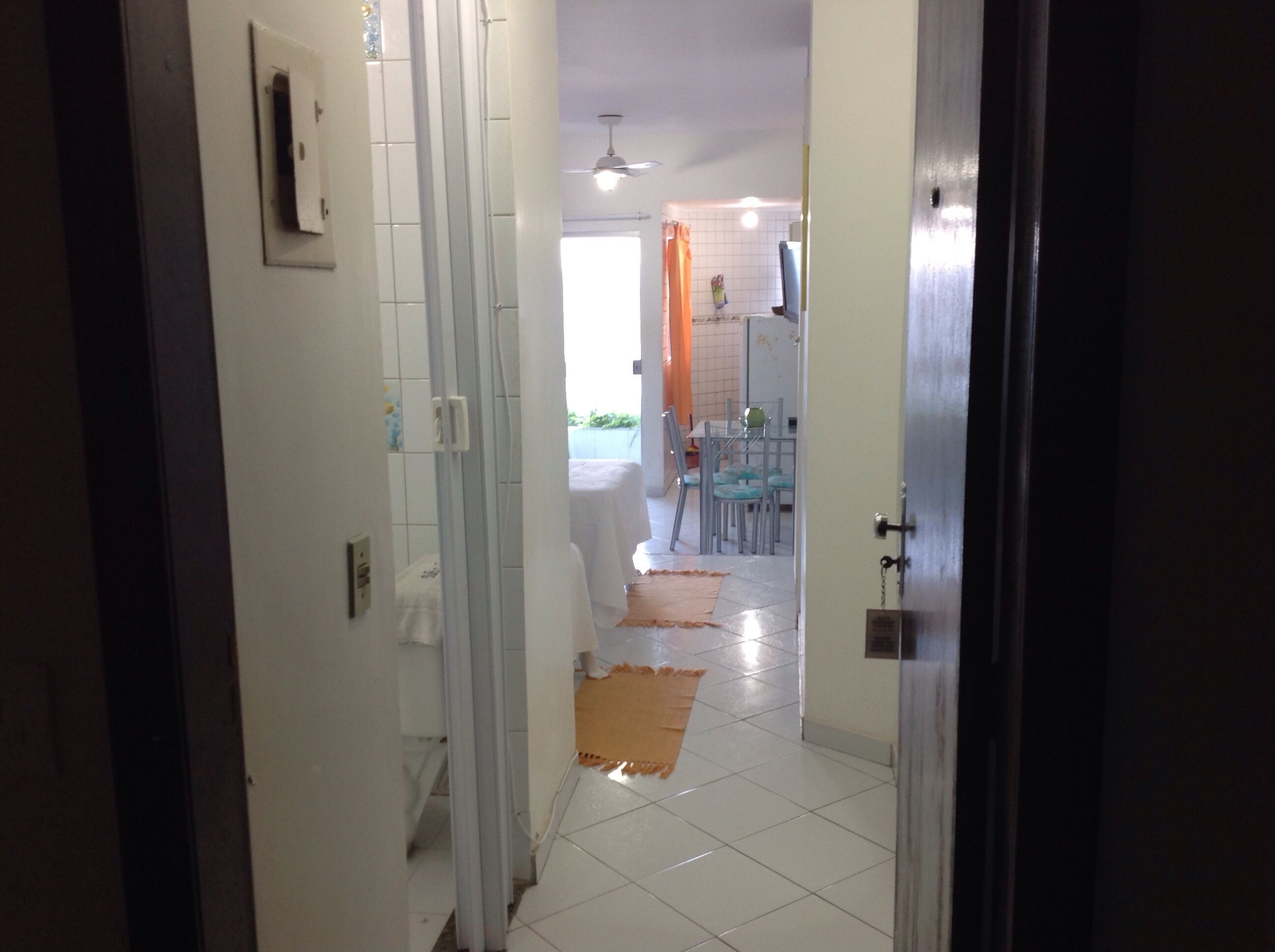 A hallway leading to a dining area with a tiled floor, a ceiling fan, and a table with chairs.