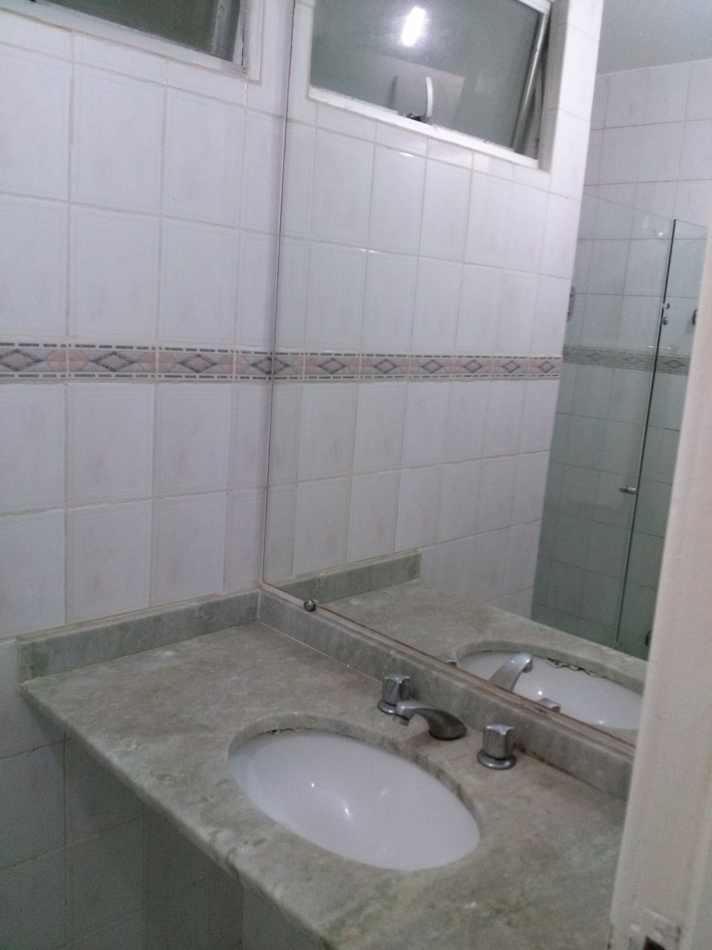 Egy fürdőszoba, amelyben mosdókagyló, tükör és zuhanyzó található.