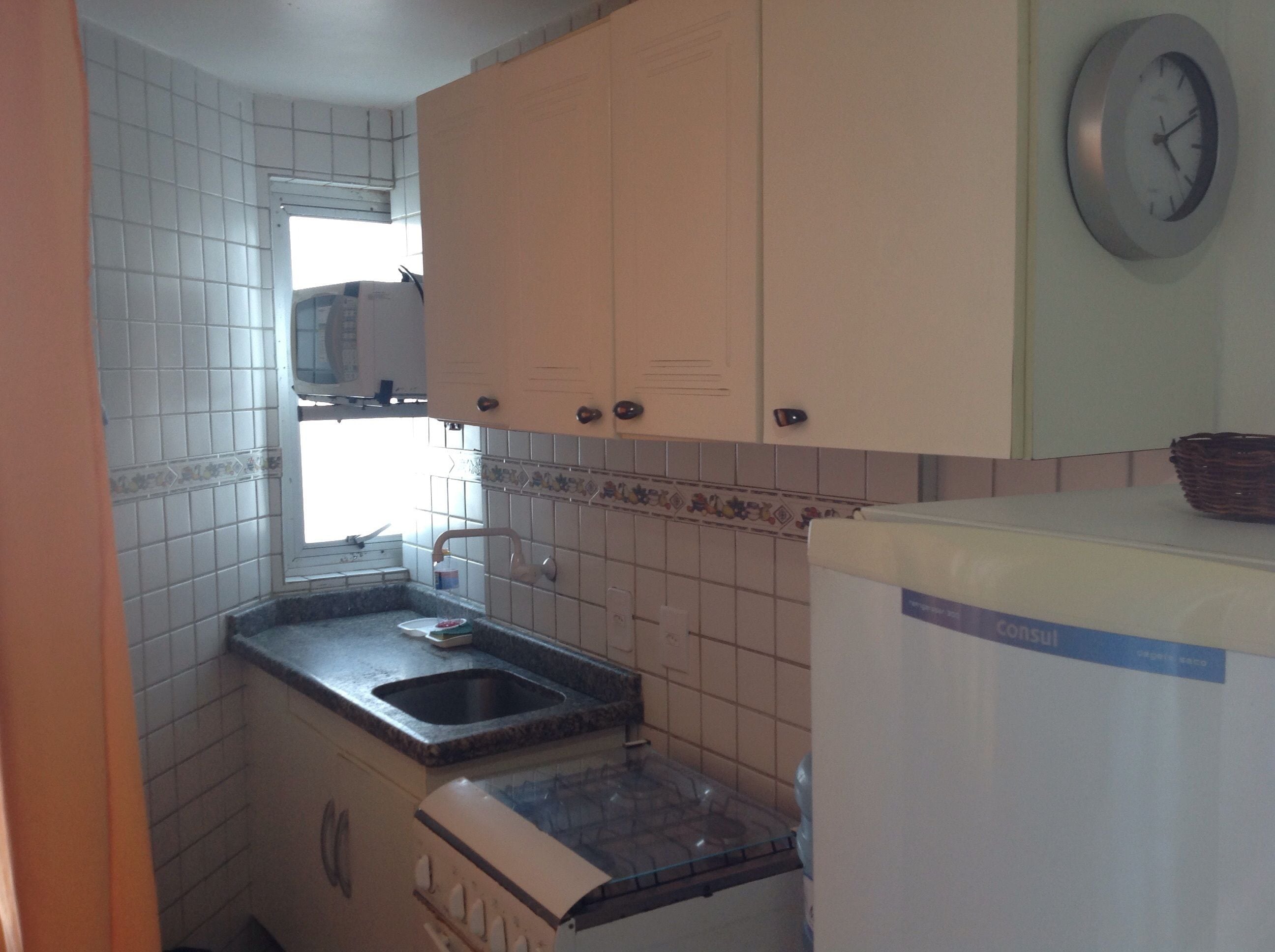 A compact kitchen with white cabinets, a sink, and a refrigerator.