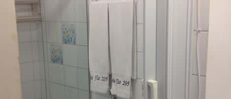 A bathroom with a glass shower enclosure, a toilet, and two towels hanging on a rack.