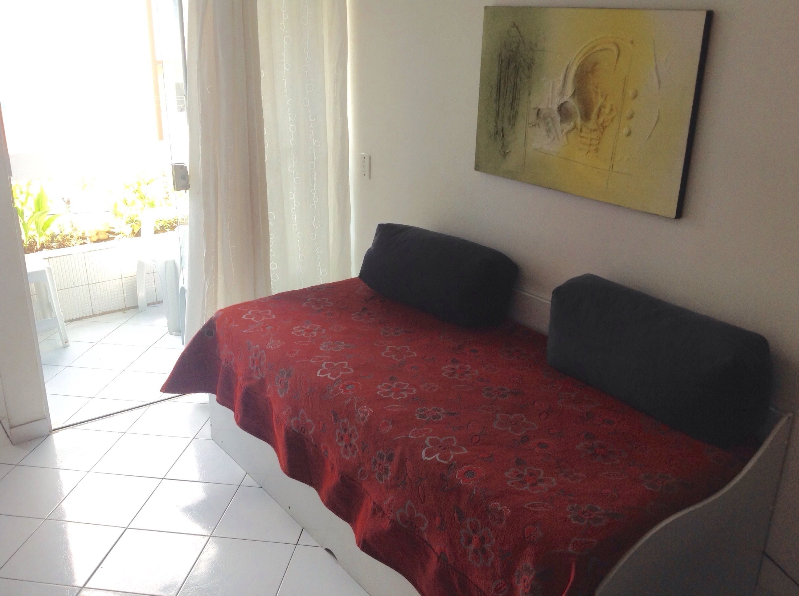 Una habitació amb un llit, un quadre a la paret i vista cap a l'exterior.