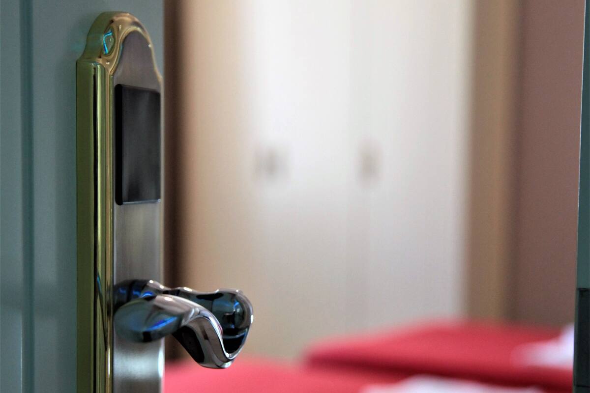 A hotel room with a bed, a wardrobe, and a door with a digital lock.